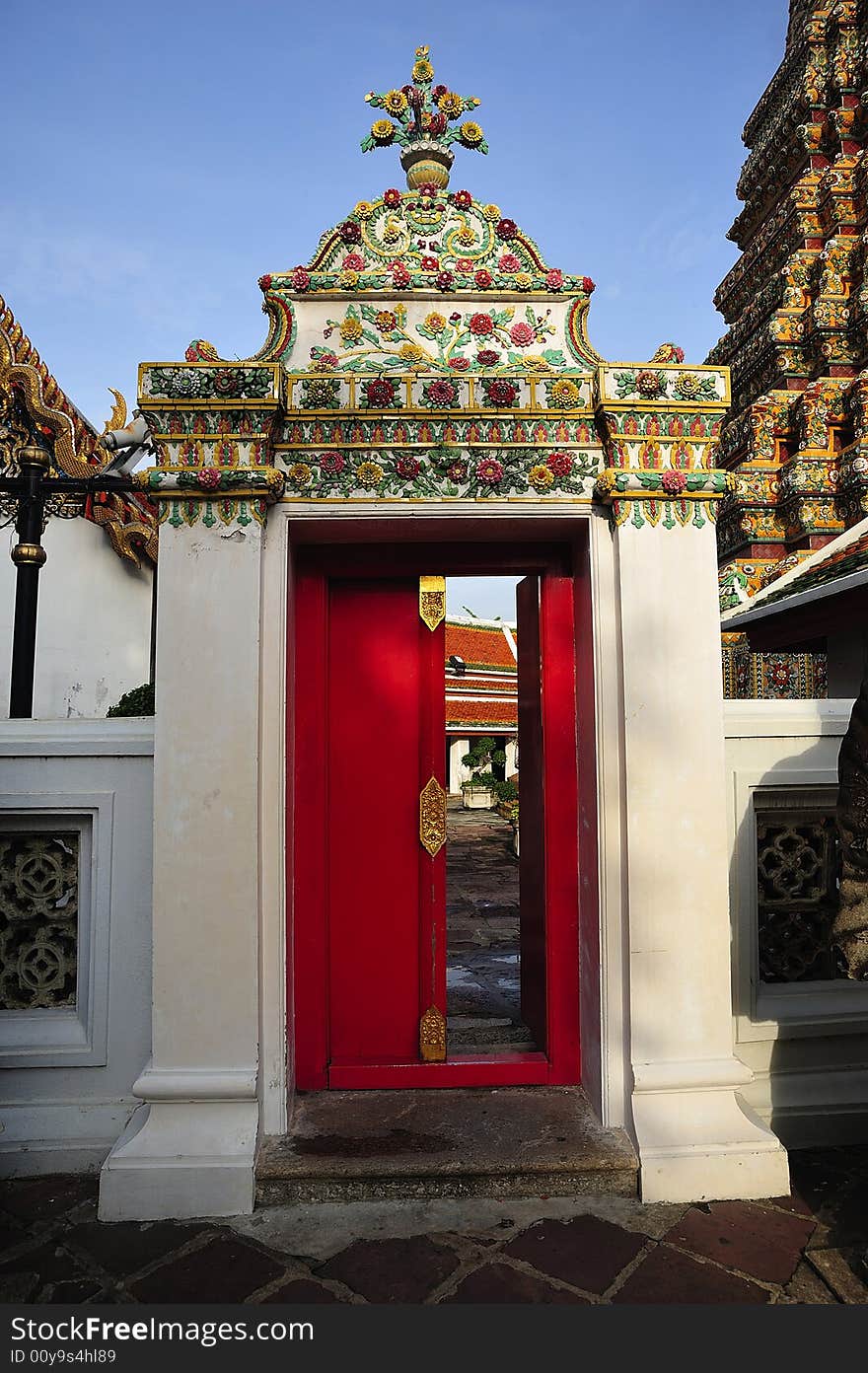 In Thailand, in Bangkok the Wat Pho is the most famous Buddhist temple. The temple is known as Wat Phra Chetuphon and houses the 46 meters long reclining Buddha. View of a courtyard red door. In Thailand, in Bangkok the Wat Pho is the most famous Buddhist temple. The temple is known as Wat Phra Chetuphon and houses the 46 meters long reclining Buddha. View of a courtyard red door