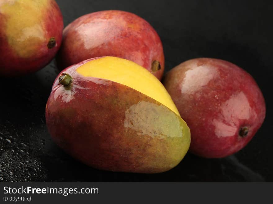 Mango on black background with water drops