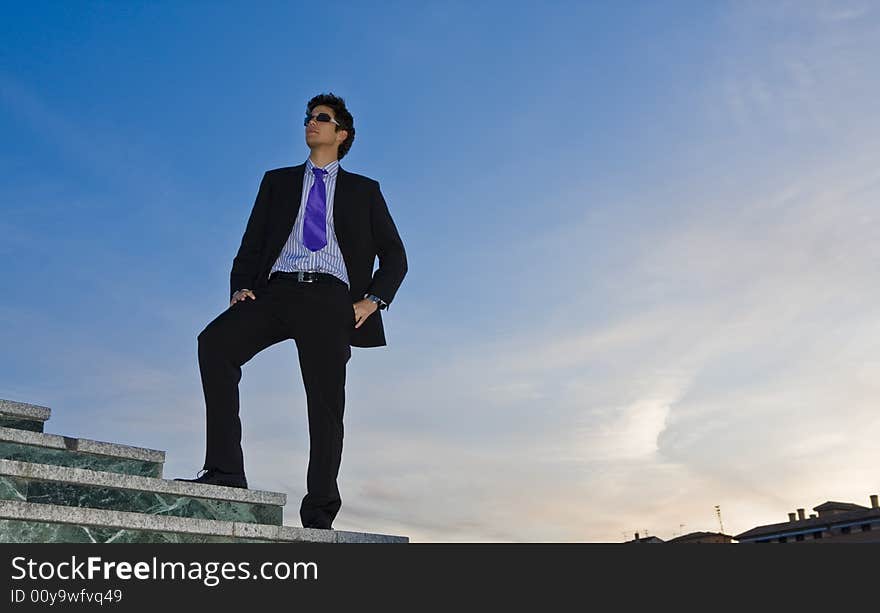 Businessman posing on stairs against blue sky. Businessman posing on stairs against blue sky.