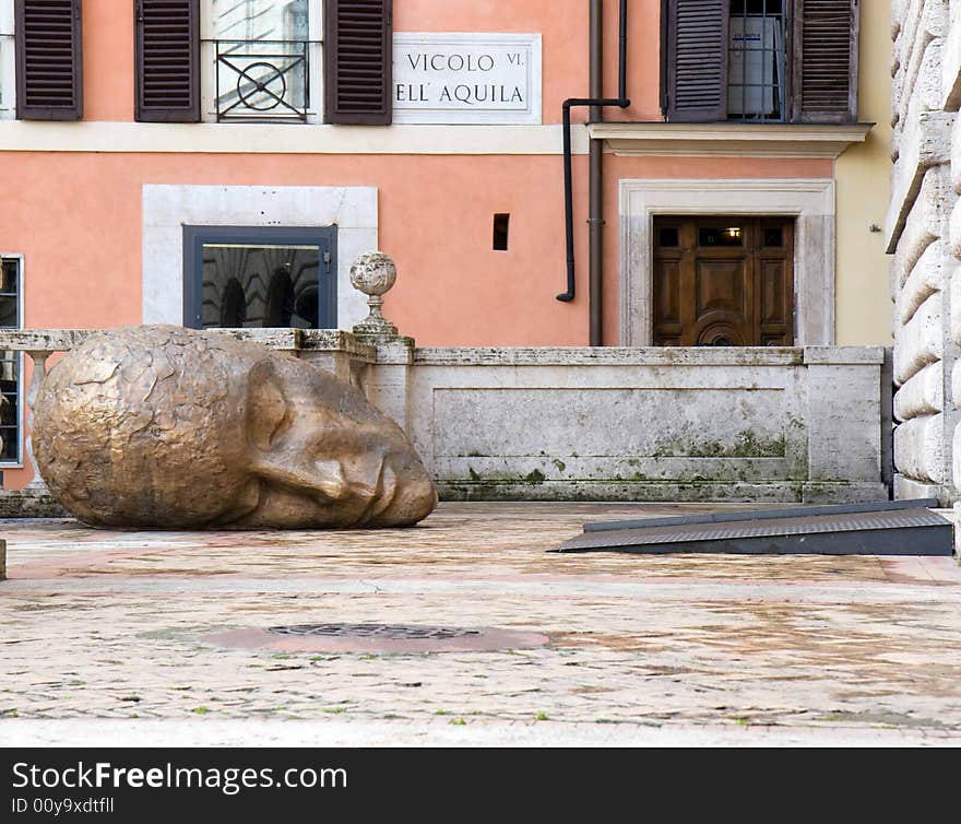 Head of a statue in a courtyard in Rome, Italy (italian street sign on the wall)