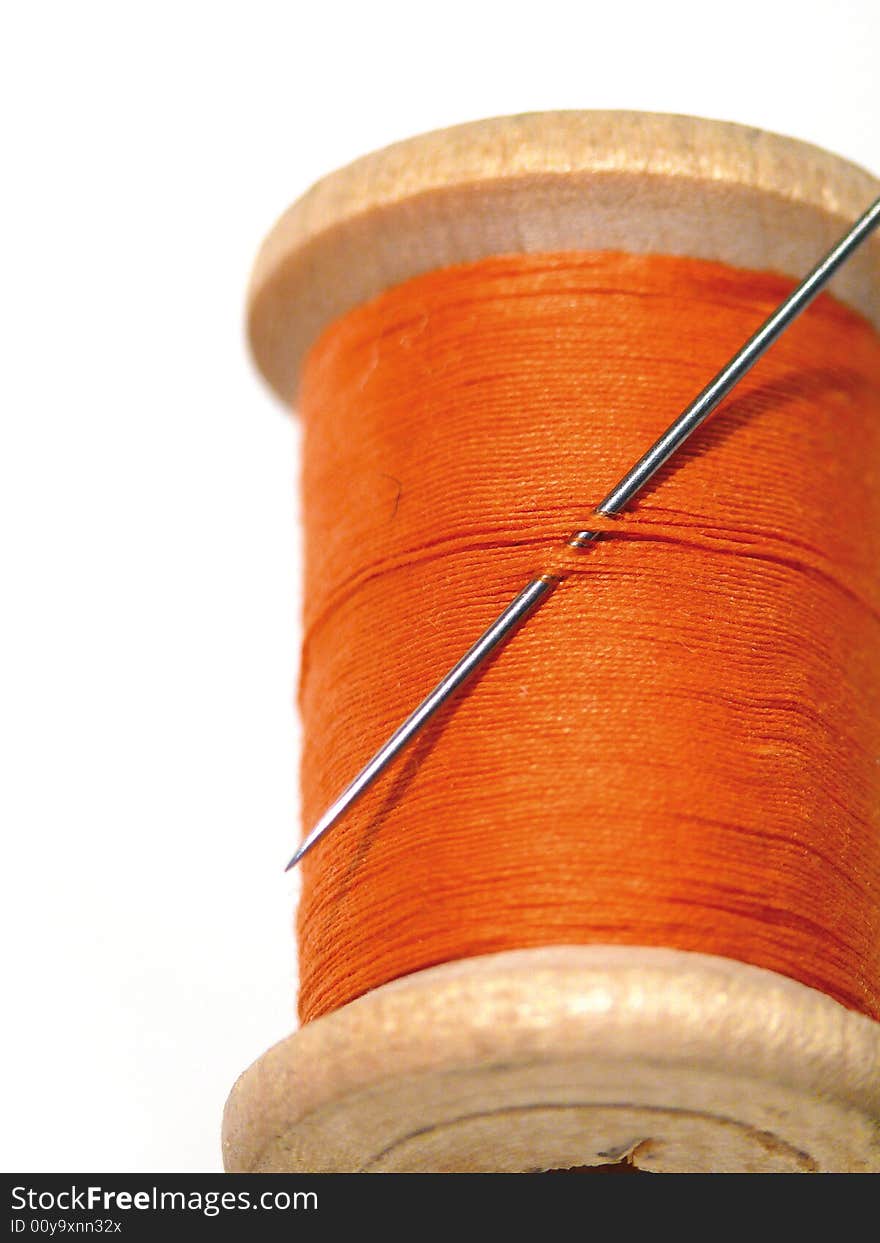 Sewing spool with a needle. A sewing needle. Color.