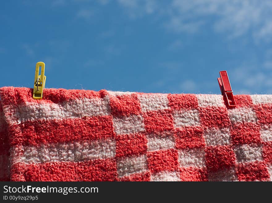 Clothes pegs holding woolen cloth on a string against the blue sky. Clothes pegs holding woolen cloth on a string against the blue sky