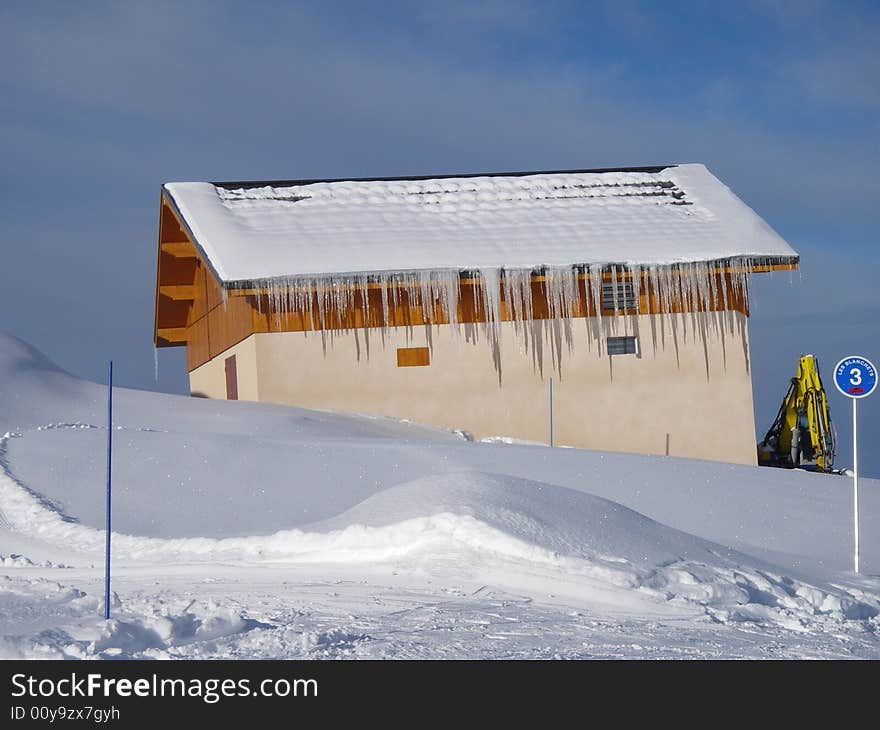 A house in mountains with icicles alongside the blue slope in Alpine resort La Plagne. A house in mountains with icicles alongside the blue slope in Alpine resort La Plagne