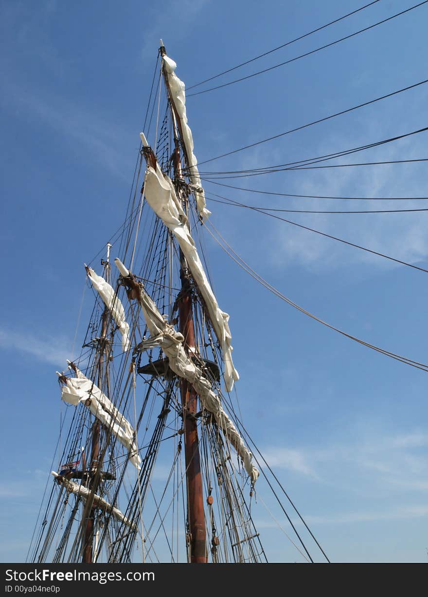 Bottom view of mast, sails and rigging of an old sailing boat  against a blue sky with some light clouds. Bottom view of mast, sails and rigging of an old sailing boat  against a blue sky with some light clouds