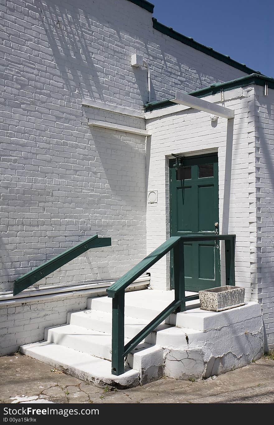 An old green door on a white painted brick building. An old green door on a white painted brick building