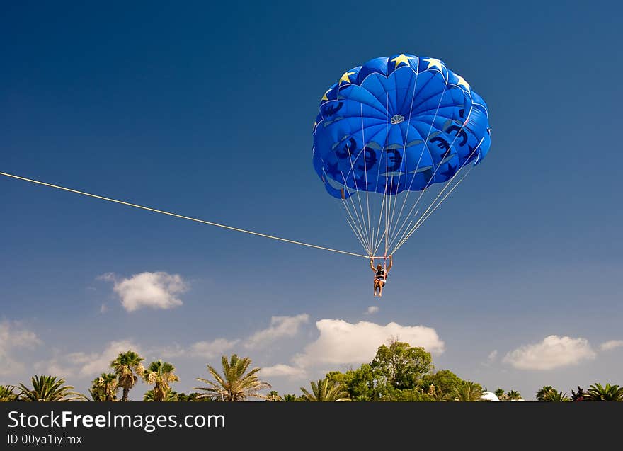 Fly over green palms on the blue parachute with EU currency symbols