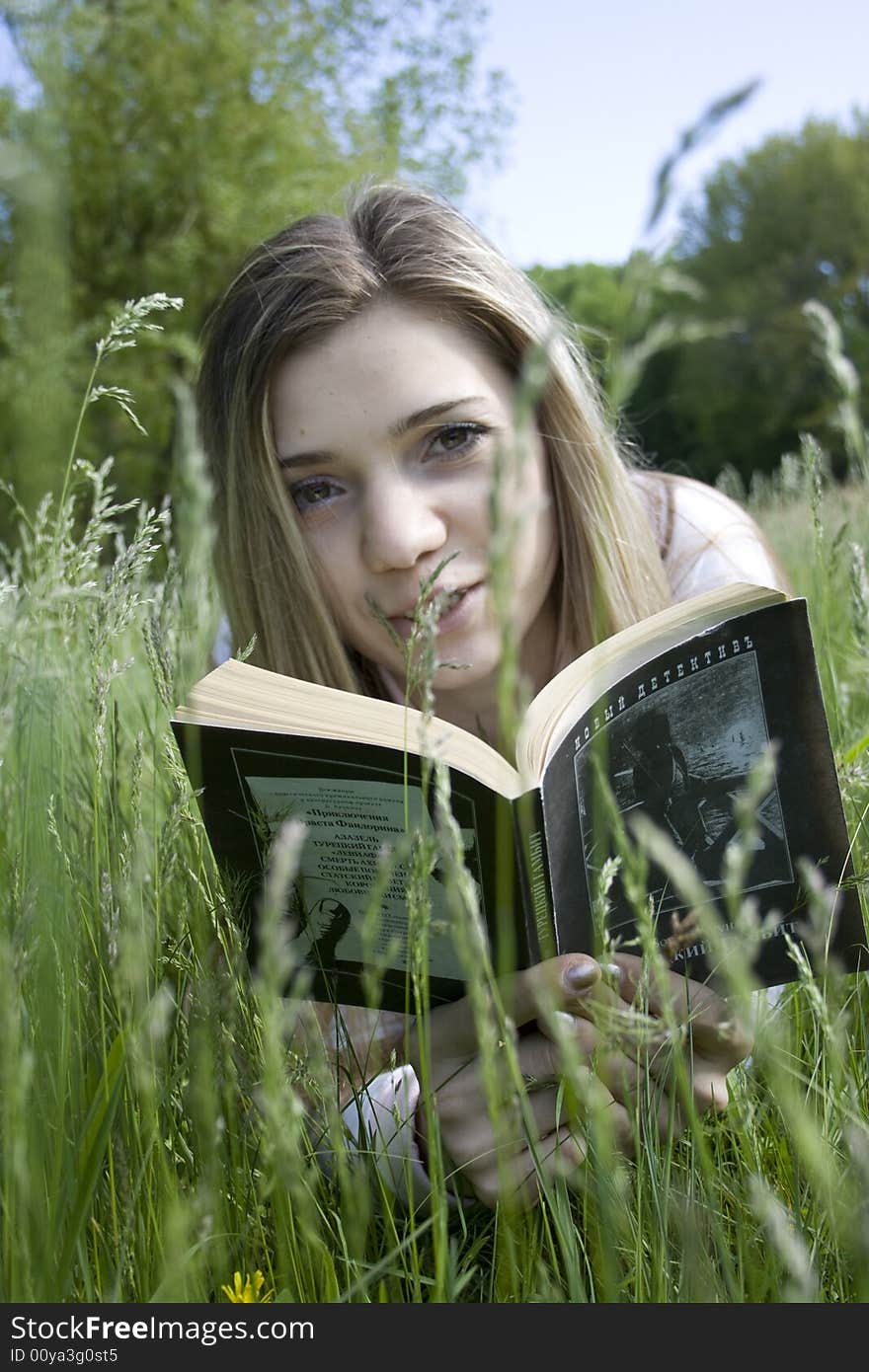 Girl on grass reading a book