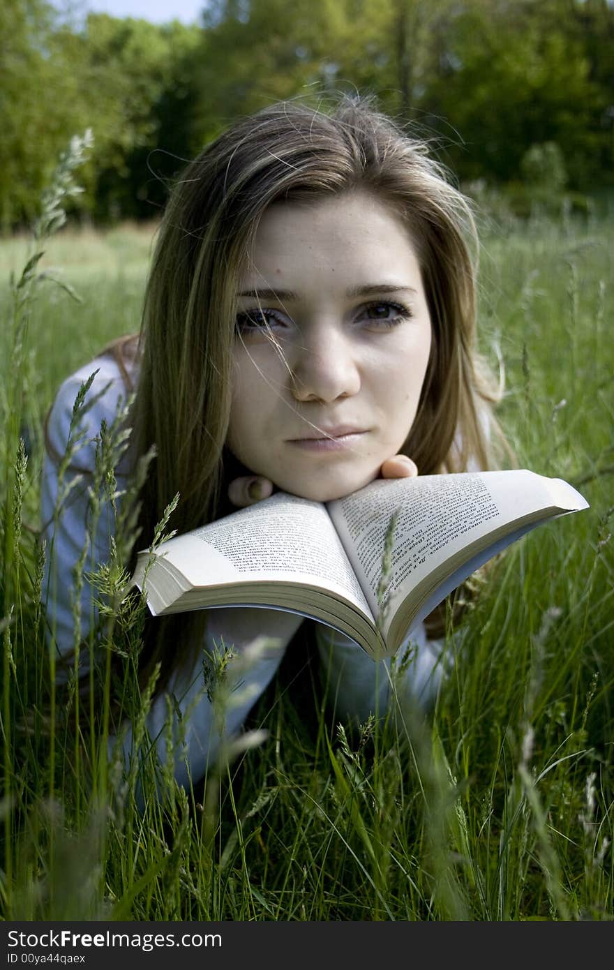 Girl reading a book on meadow