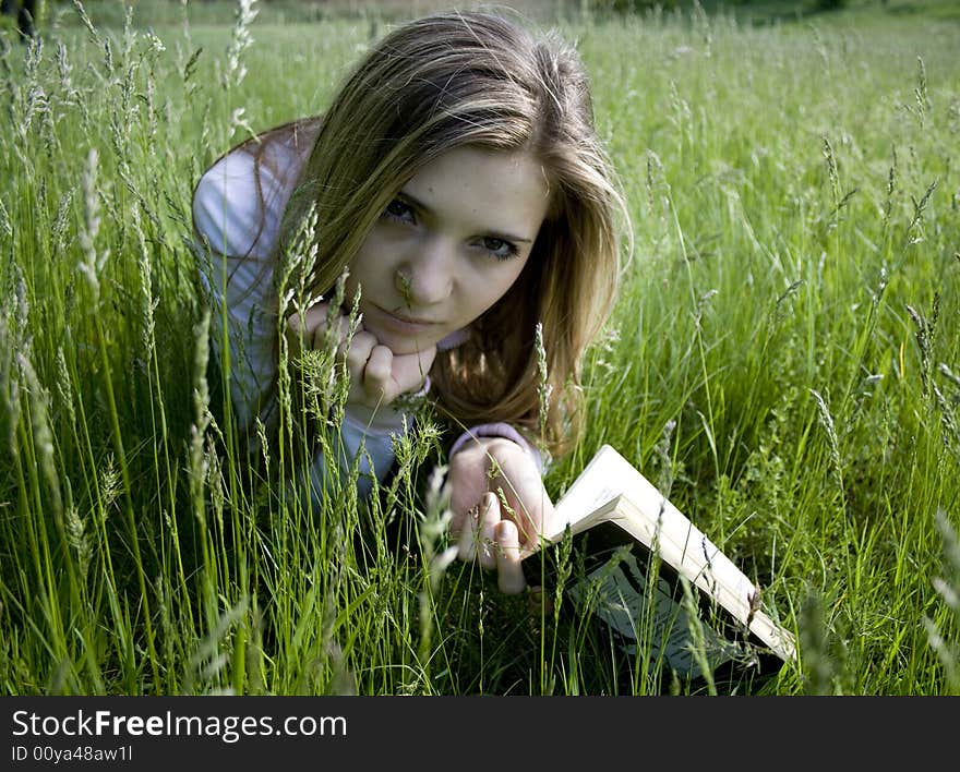 Girl reading a book on meadow