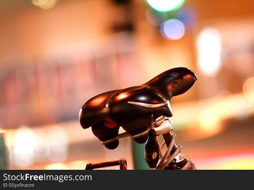 Bike seat set against blurred lights at night. Space for copy