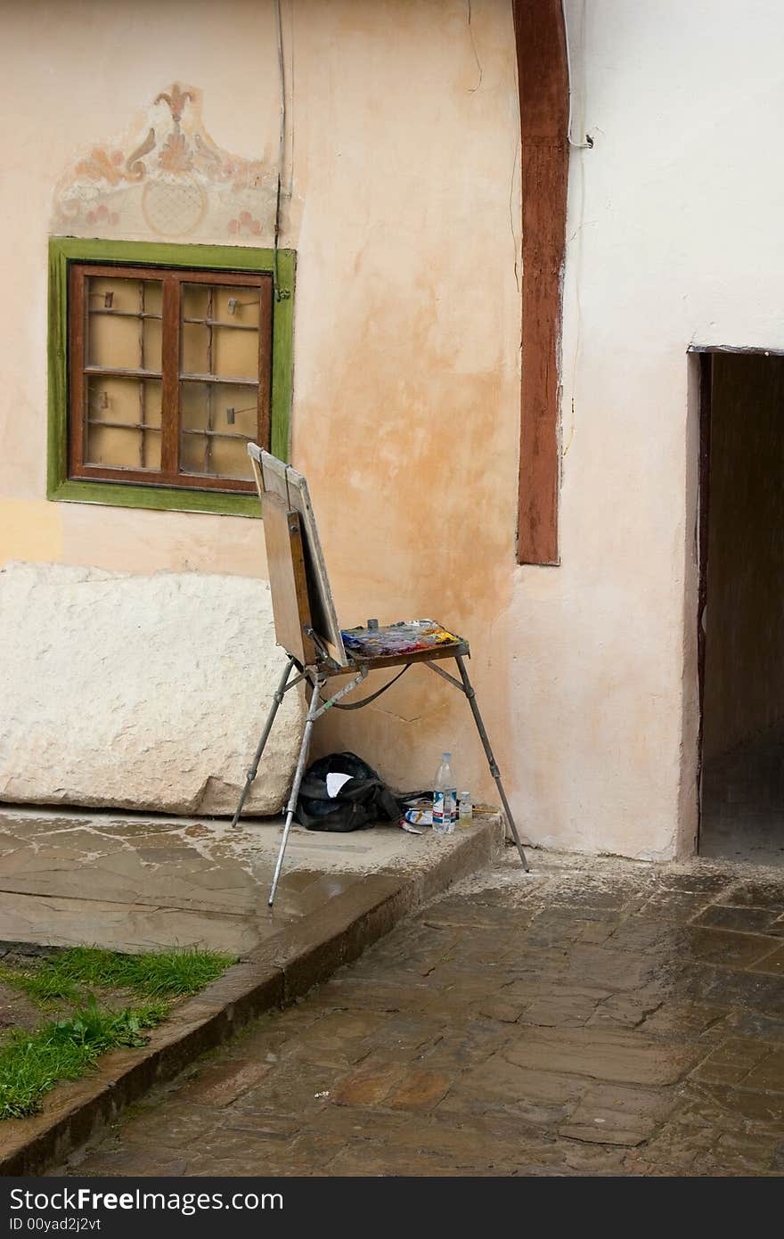 Easel and paints on the vintage stucco wall background. Easel and paints on the vintage stucco wall background