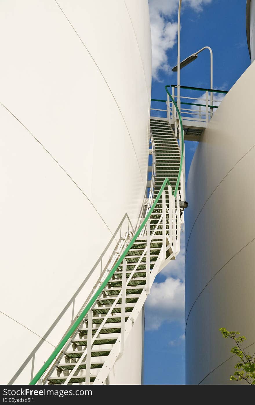 Up view of industry staircase between gas tanks