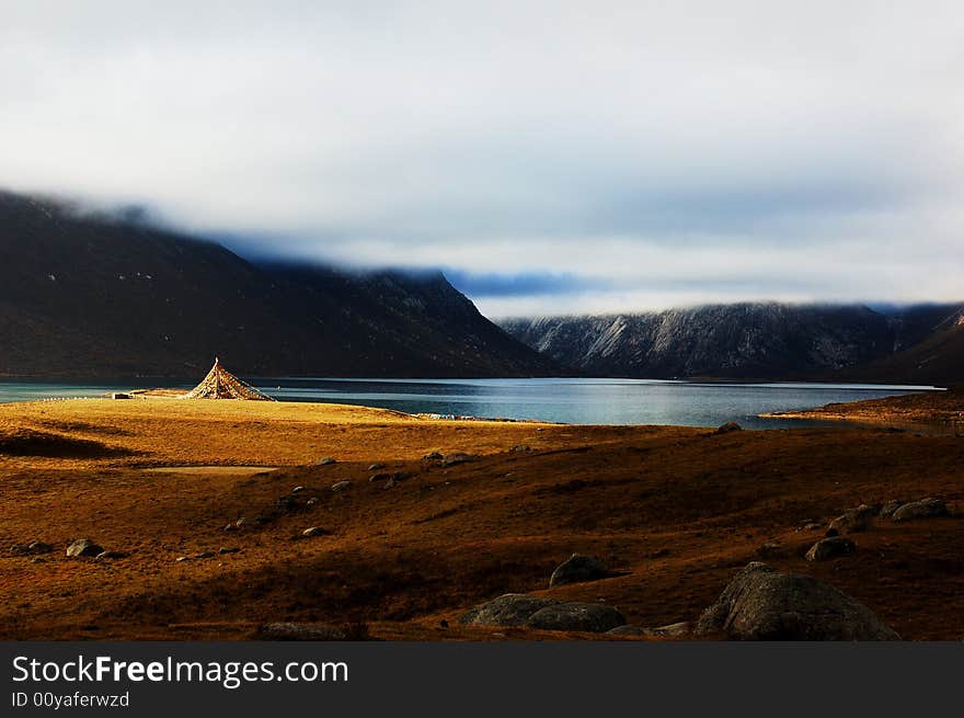 When travelling in Tibet of China, a beautiful lake appears in front of us, and the meadows in autumn is so beautiful too, with a flag on it. When travelling in Tibet of China, a beautiful lake appears in front of us, and the meadows in autumn is so beautiful too, with a flag on it.