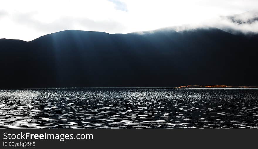 When travelling in Tibet of China, a  beautiful lake beside the mountains appears in front of us, and the sunshine irradiates the water. When travelling in Tibet of China, a  beautiful lake beside the mountains appears in front of us, and the sunshine irradiates the water.