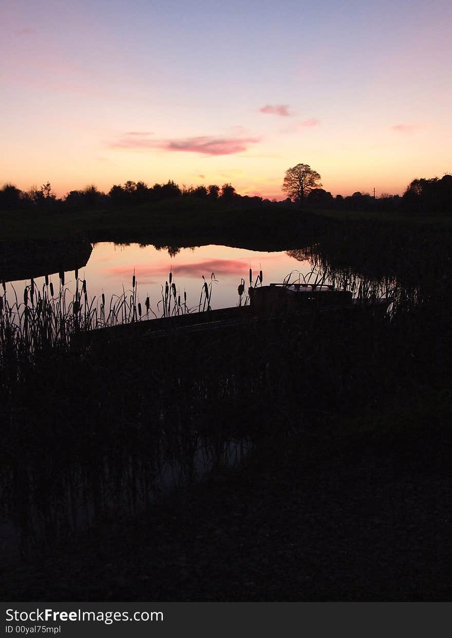 Small boat nestled in reeds by waters edge at dusk. Small boat nestled in reeds by waters edge at dusk.