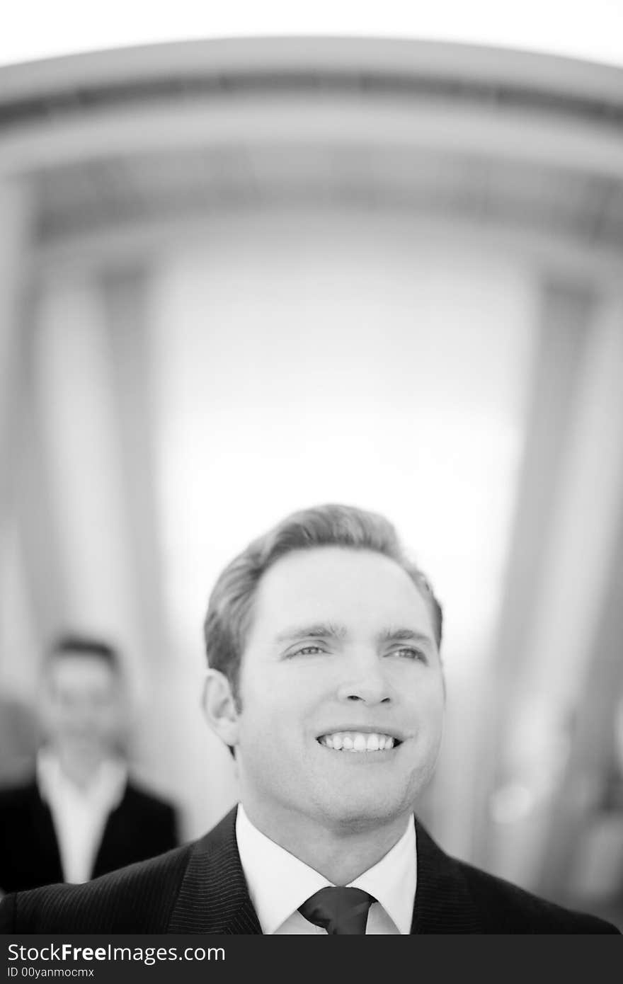 Front view of young businessman standing wearing suit with businesswoman standing behind him. Front view of young businessman standing wearing suit with businesswoman standing behind him