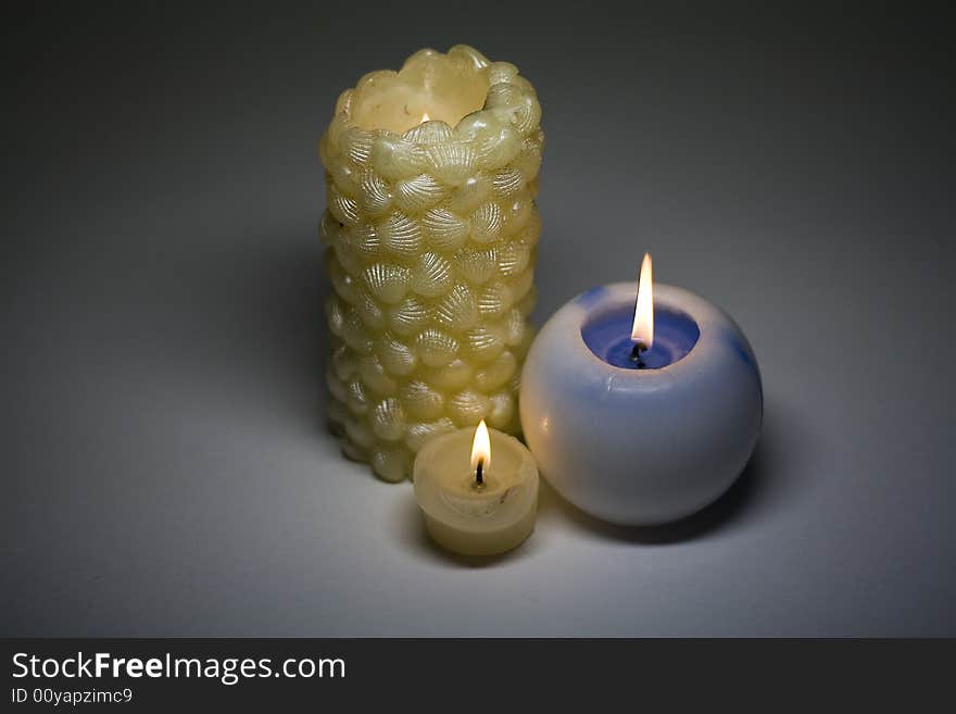 Three burning candles on a grey background. Three burning candles on a grey background