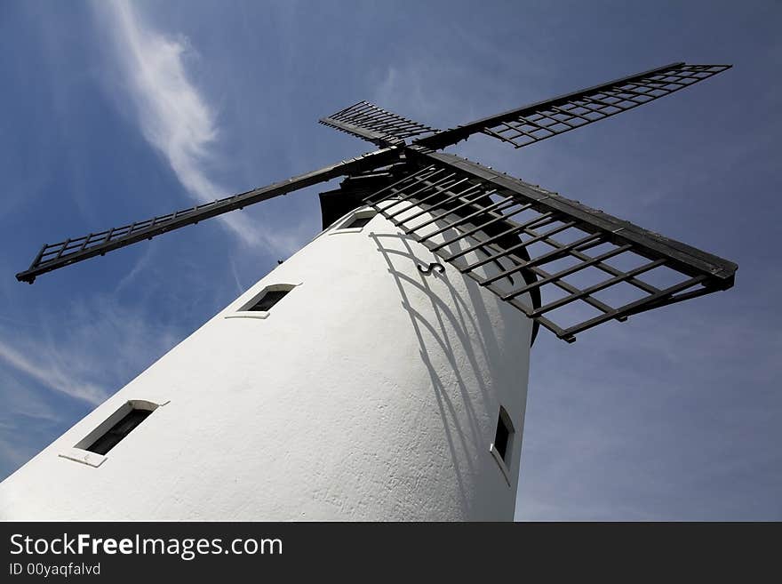 White windmill with black sails against blue sky