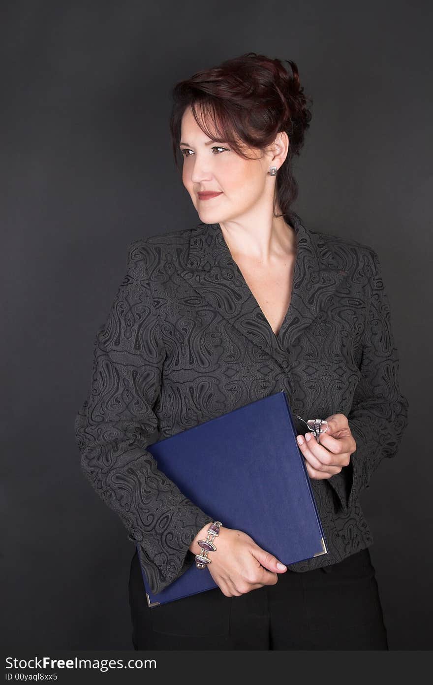 Composed Businesswoman holding a blue file against a black background. Composed Businesswoman holding a blue file against a black background