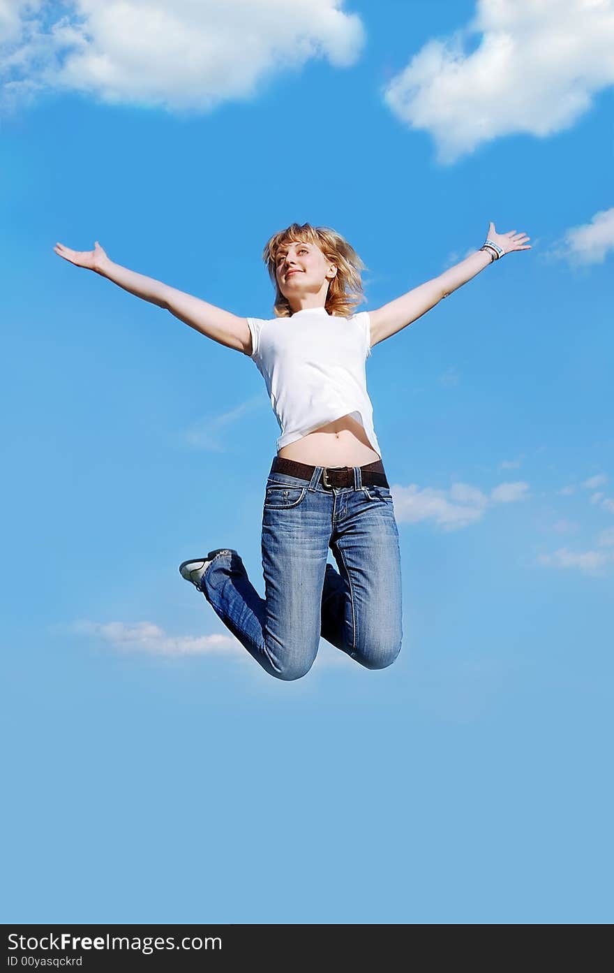 Happy young  woman in white t-shirt jumping high at the blue clear sky background. Happy young  woman in white t-shirt jumping high at the blue clear sky background