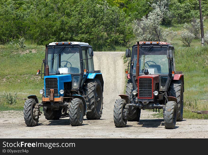 Two dusty wheeled tractors at countryside, ready to work. Two dusty wheeled tractors at countryside, ready to work