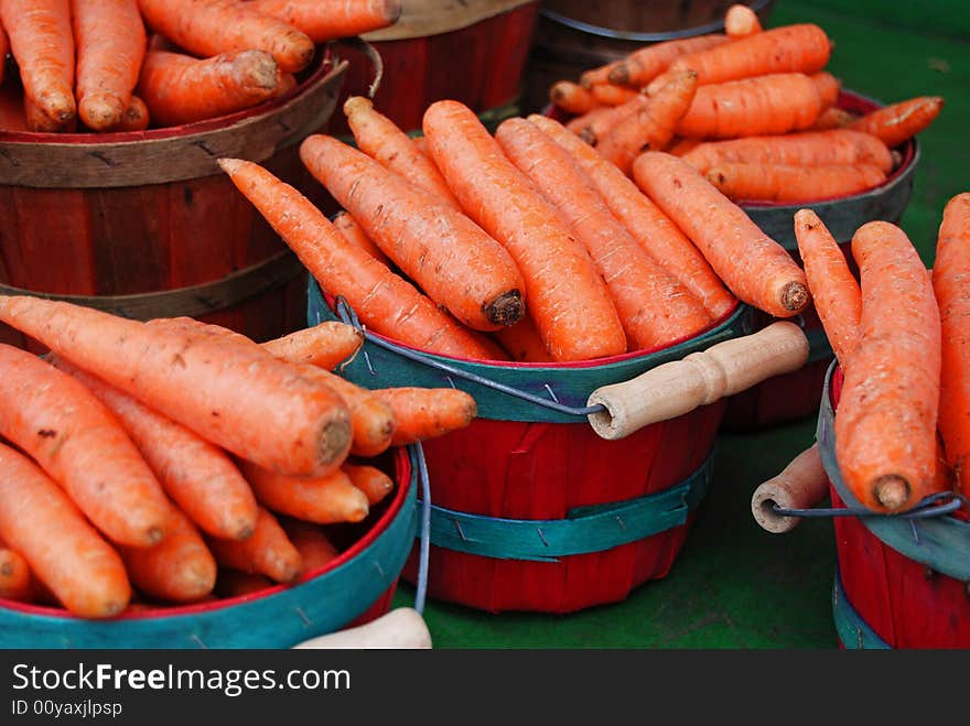 Baskets of raw carrots in baskets at a farmer' market. Baskets of raw carrots in baskets at a farmer' market.