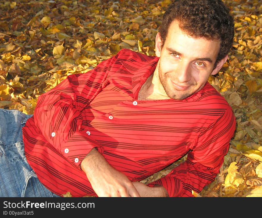 The young man is lying on the grass in the park. The young man is lying on the grass in the park