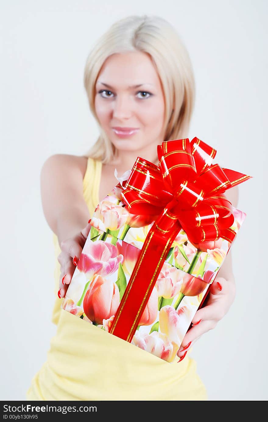 Smiling blond dressed in yellow shirt with big gift box in hands. Smiling blond dressed in yellow shirt with big gift box in hands