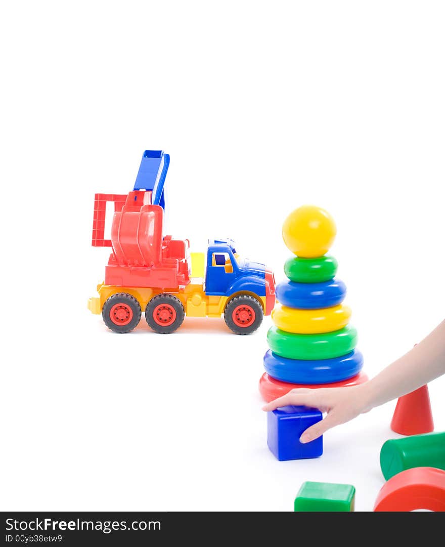 Mother's hand put cube on floor and invite baby to play with toys on playground. Image with copyspace isolated on white with light shadows. Mother's hand put cube on floor and invite baby to play with toys on playground. Image with copyspace isolated on white with light shadows