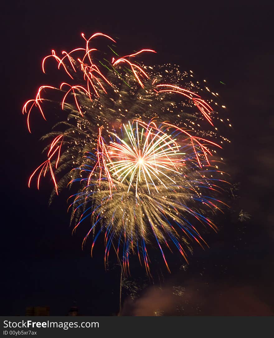 Multiple colourful fireworks explosions on black night sky.