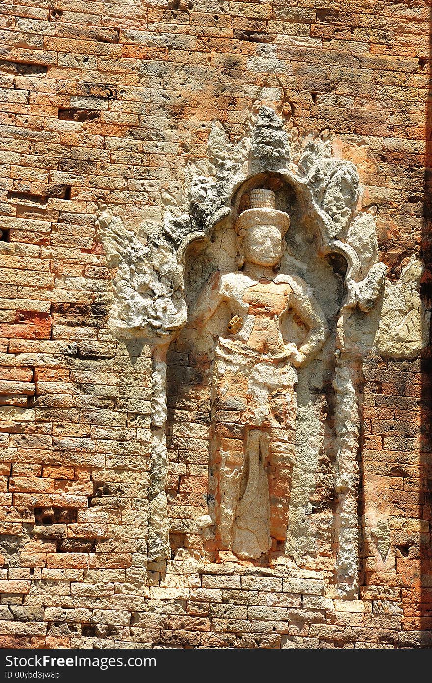 In Cambodia in the ancient city of Roulos the Hindu temple of Bakong was built in the 9th century by the king Indravarman I. View of a carved wall with a khmer guardian. In Cambodia in the ancient city of Roulos the Hindu temple of Bakong was built in the 9th century by the king Indravarman I. View of a carved wall with a khmer guardian