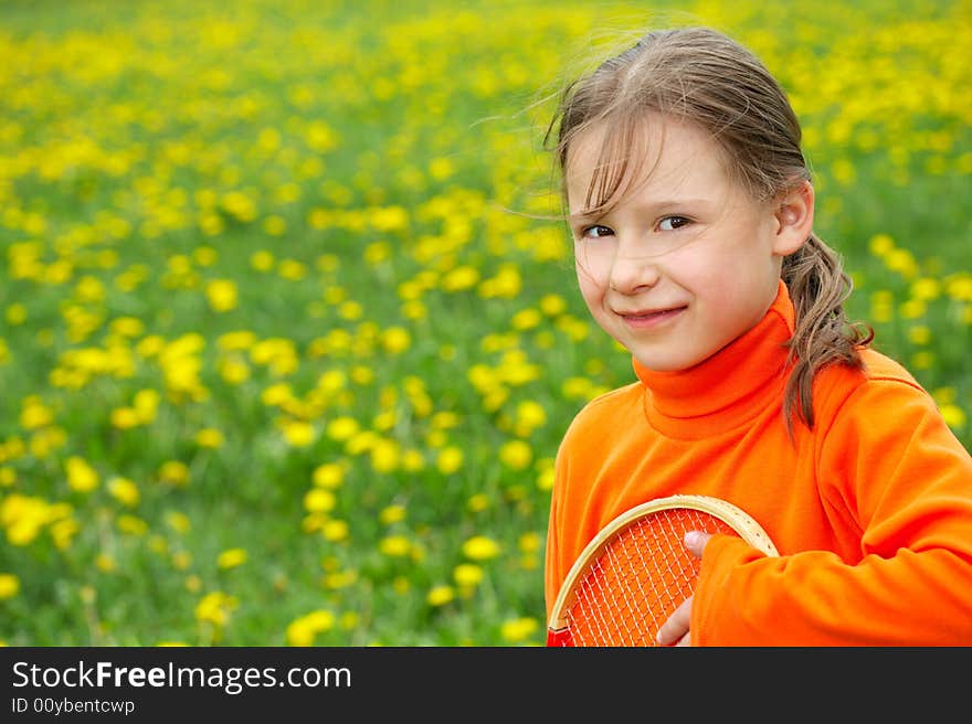 The little girl in orange clothes holds a tennis racket. The little girl in orange clothes holds a tennis racket