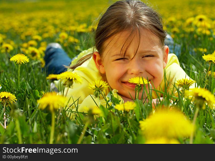 The little girl lays on a lawn among yellow flowers. The little girl lays on a lawn among yellow flowers