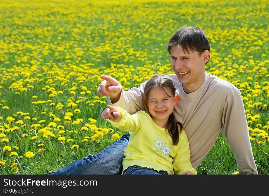 The father with a daughter sit on a lawn and show in a distance. The father with a daughter sit on a lawn and show in a distance