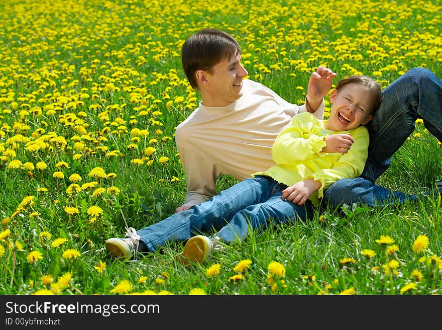 Father with daughter sit on a lawn and laugh. Father with daughter sit on a lawn and laugh