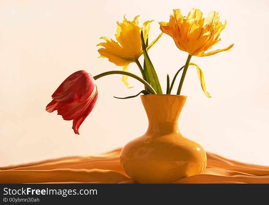 Three tulips in yellow vase on beige background. Three tulips in yellow vase on beige background