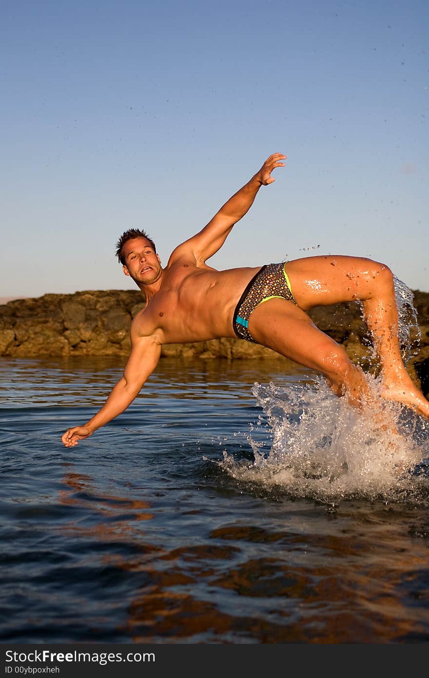 Young athetlic man jumping in the sea water. Young athetlic man jumping in the sea water