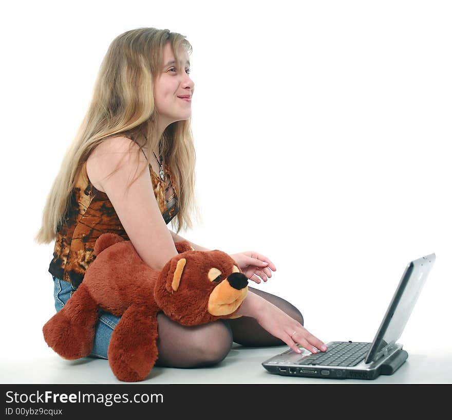 The girl with a toy looks the laptop and smiles. The girl with a toy looks the laptop and smiles
