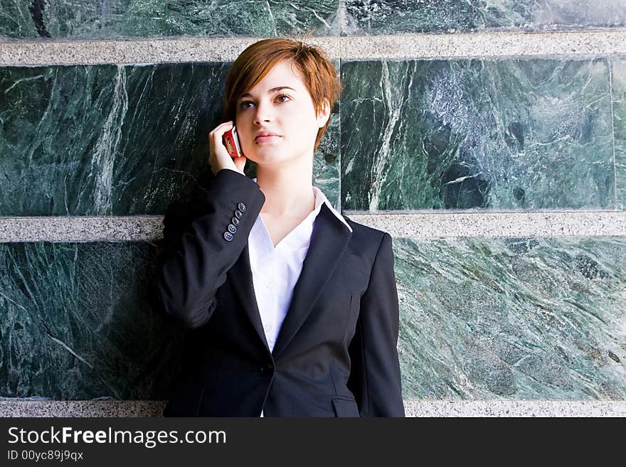 Beautiful businesswoman at phone over marble background.