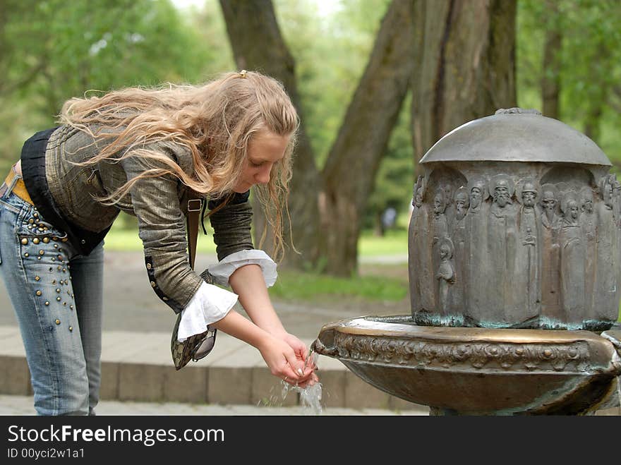 The beautiful girl types water in hands. The beautiful girl types water in hands