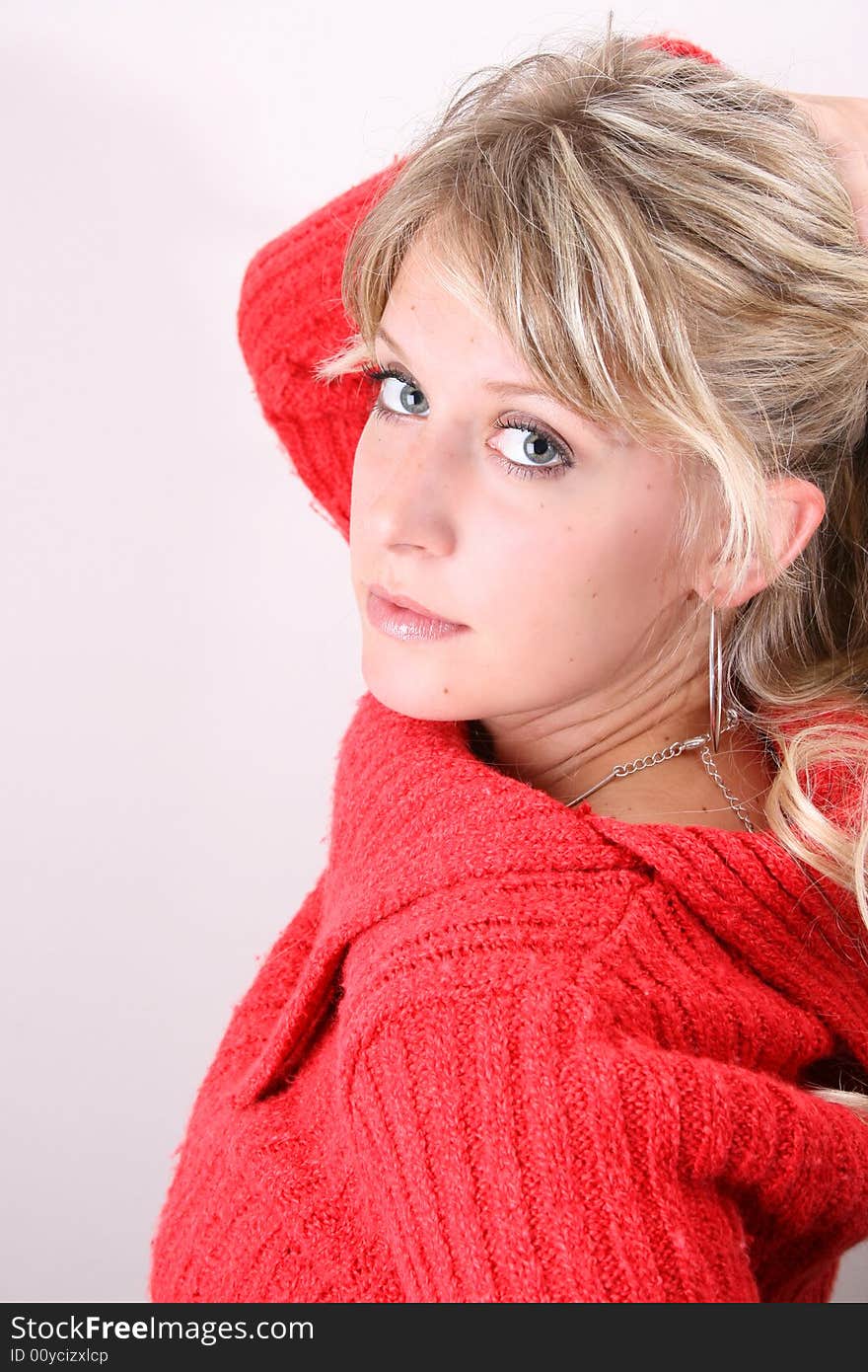 Blonde model tying her hair, wearing a red top. Blonde model tying her hair, wearing a red top