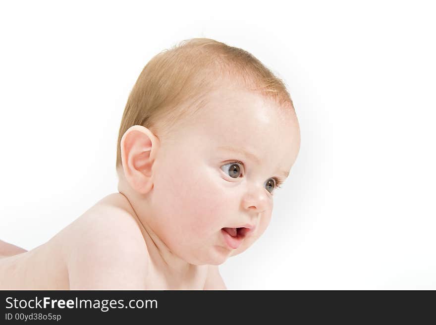 Naked six months old baby lying on his bally isolated on white