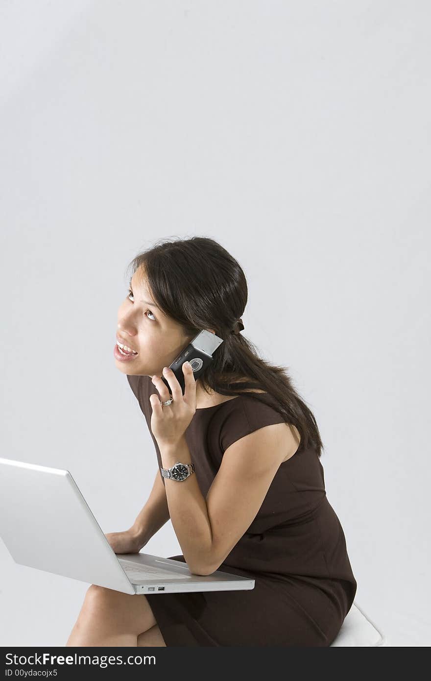 Asian woman using cell phone and laptop looking up thinking. Asian woman using cell phone and laptop looking up thinking.