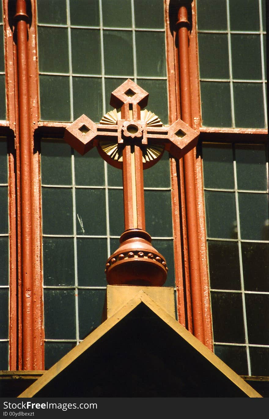 Detail of church cross in front of window. Detail of church cross in front of window