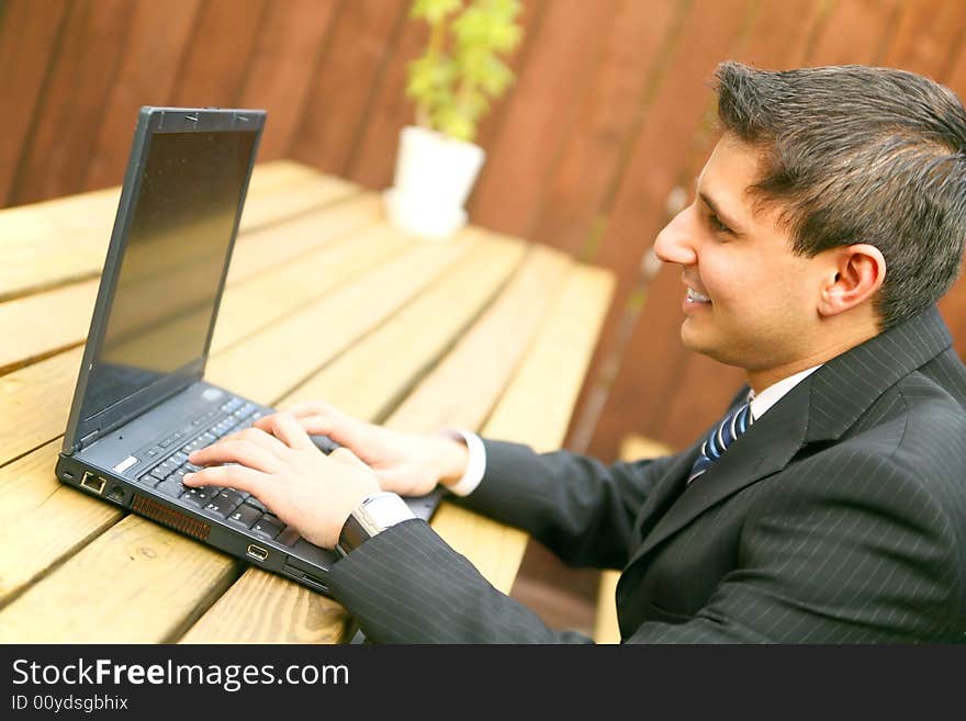 Businessman smiling while working on his laptop outdoor. Businessman smiling while working on his laptop outdoor