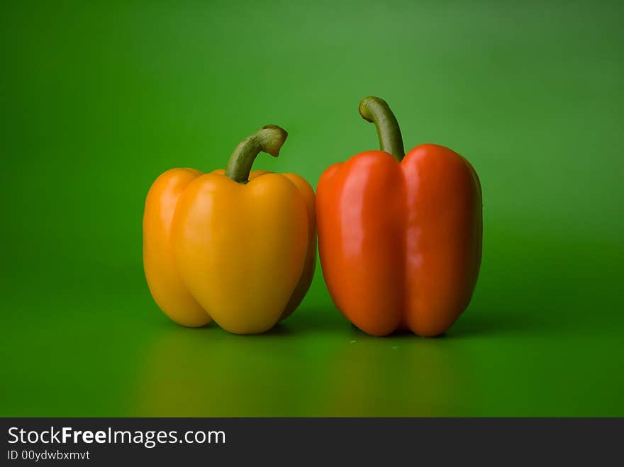 Yellow and orange paprika on the green background