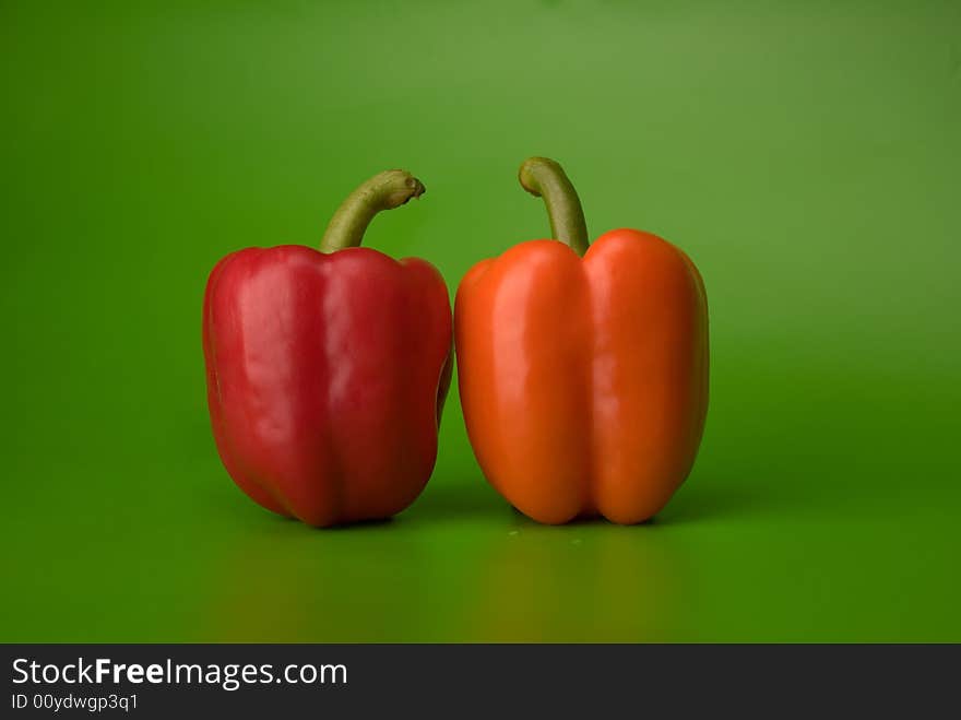 Red and orange paprika on the green background