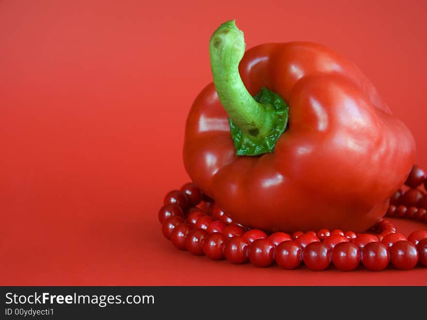 Red paprika and red beads on the red background. Red paprika and red beads on the red background