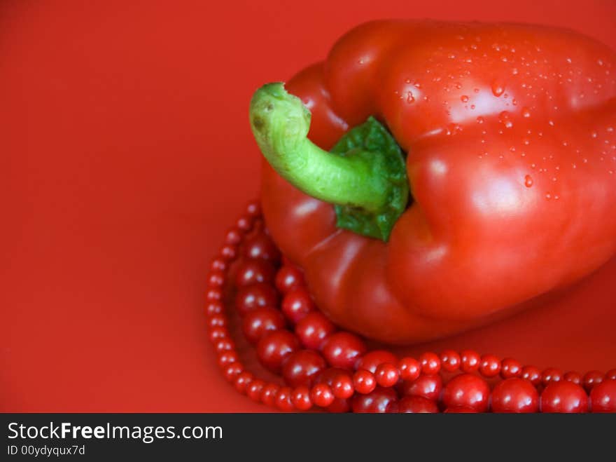 Red paprika and beads on the red background