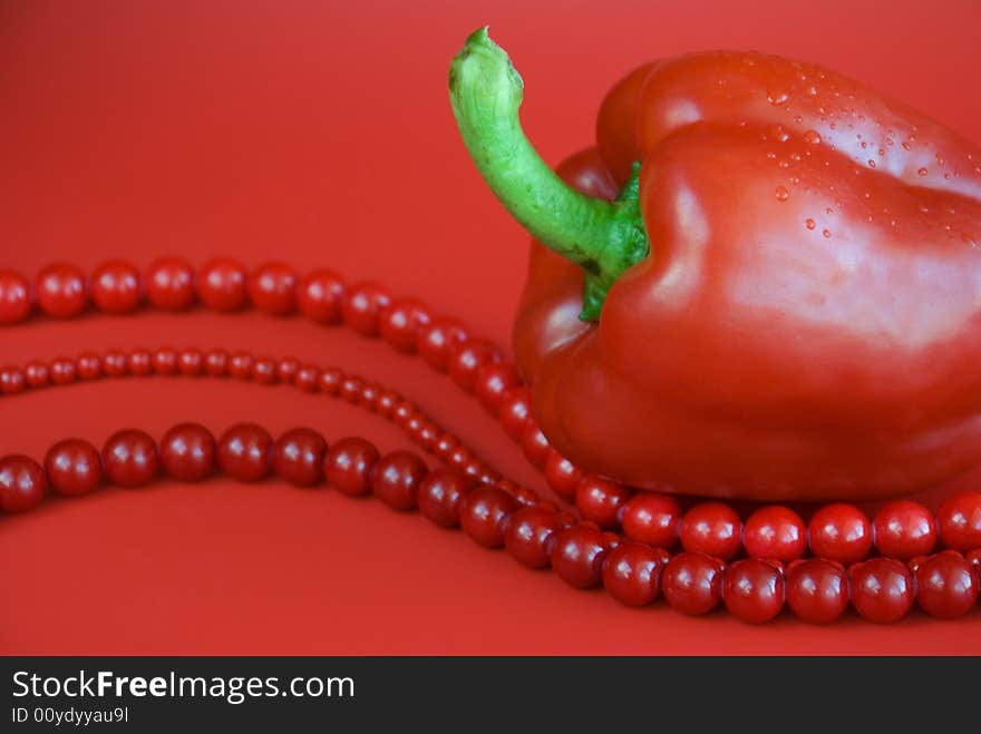 Red paprika and red beads with drops of water